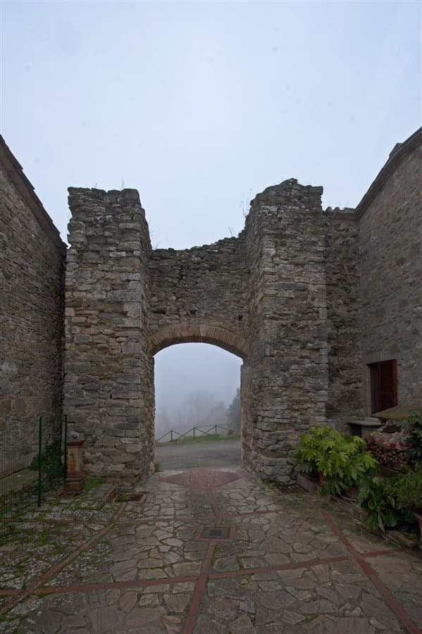 Arco in pietra ad Assignano, con la nebbia oltre la soglia.