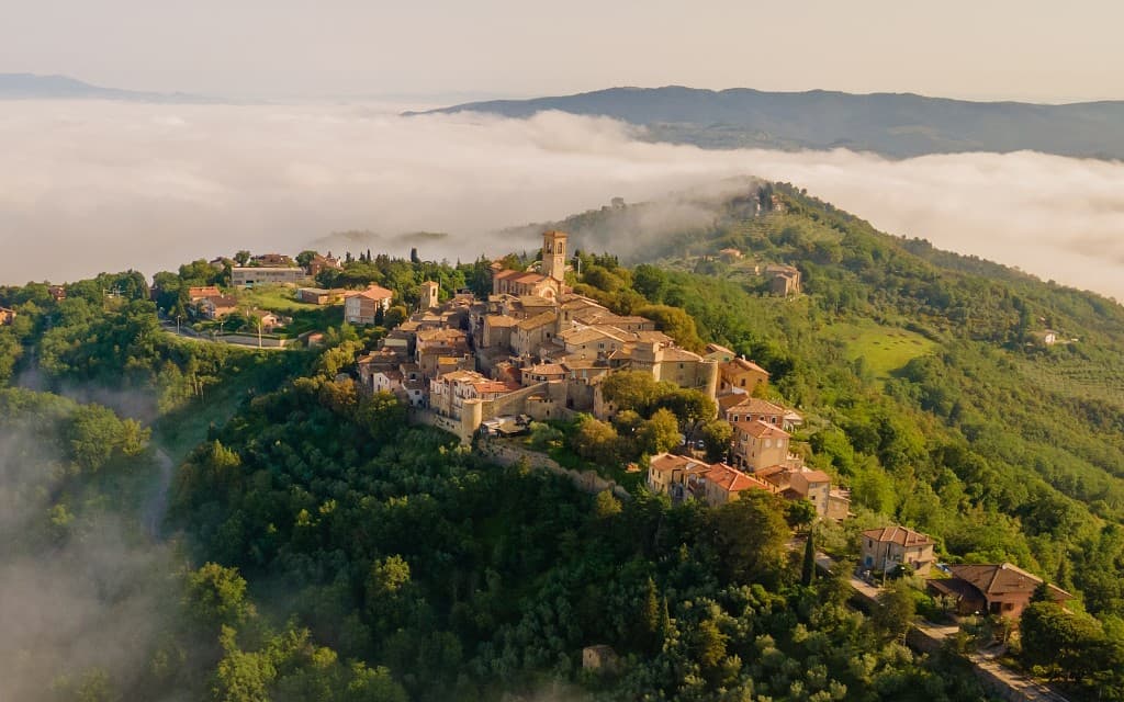Collazzone visto dall'alto, tra oliveti e un mare di nebbia.
